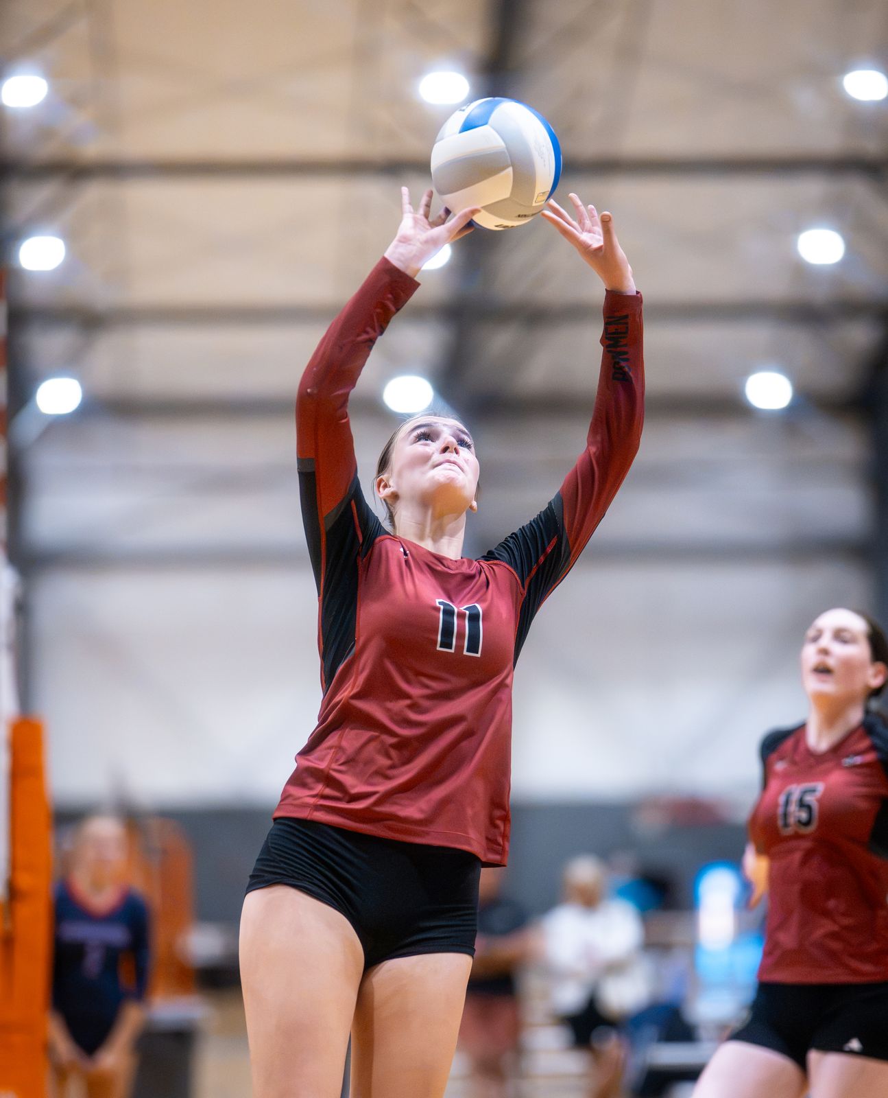 A setter in maroon squares up to set the ball