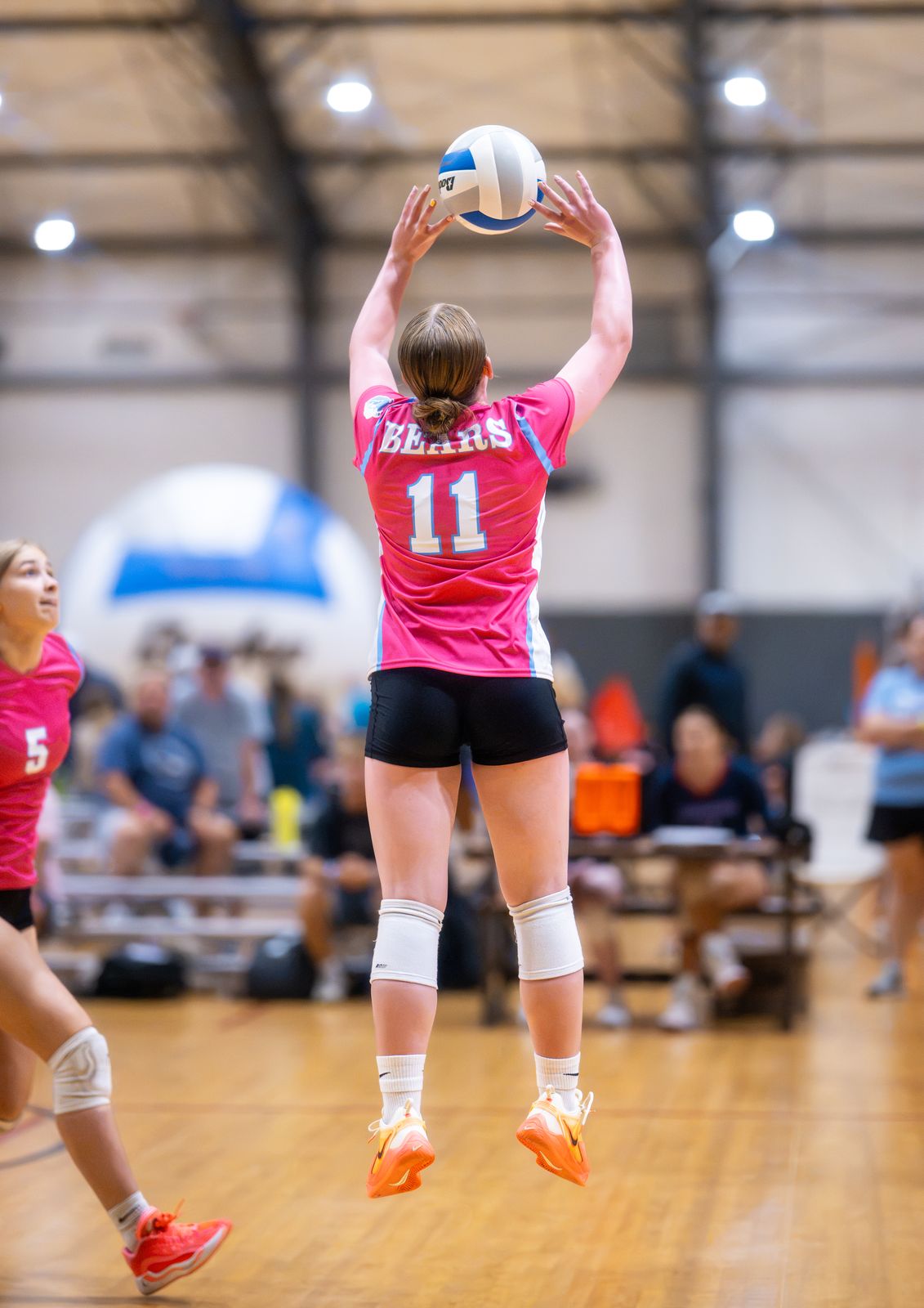 A setter in pink jumps to set